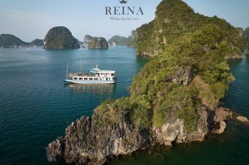 The Reina cruise ship sailing among the beautiful small rock islands in Halong Bay, showcasing the stunning natural beauty of the area