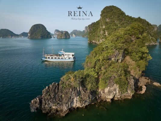The Reina cruise ship sailing among the beautiful small rock islands in Halong Bay, showcasing the stunning natural beauty of the area