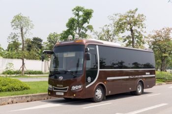 16-seater Felix Limousine van parked on a road with greenery in the background, used for comfortable travel between Halong Bay and Ninh Binh