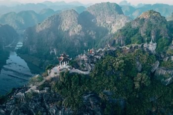 Aerial view of the majestic karst mountains and ancient temples of Ninh Binh, Vietnam, shrouded in mist and lush greenery