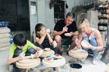 Tourists painting ceramics and lacquerware at Bat Trang village, highlighting traditional Vietnamese art.