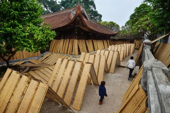 Traditional bamboo weaving in a narrow alley at Tho Ha village, showcasing Vietnamese handicraft culture.